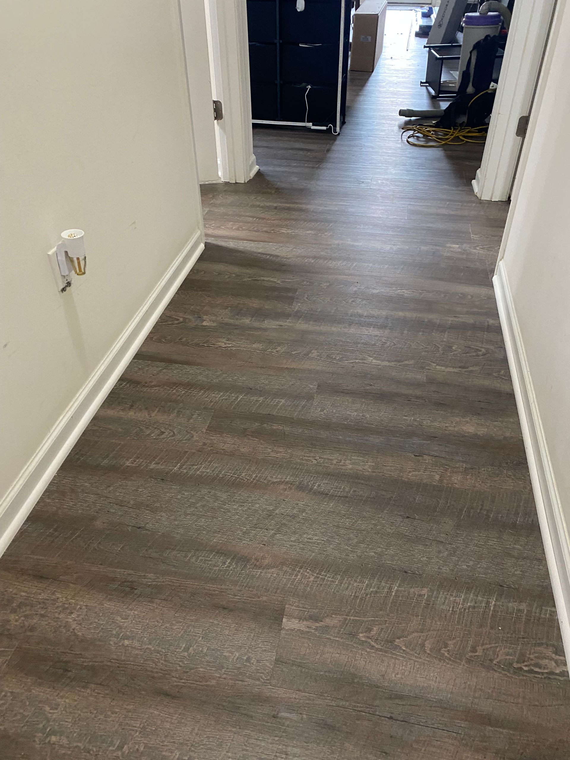 A hallway with a wooden floor and white trim.