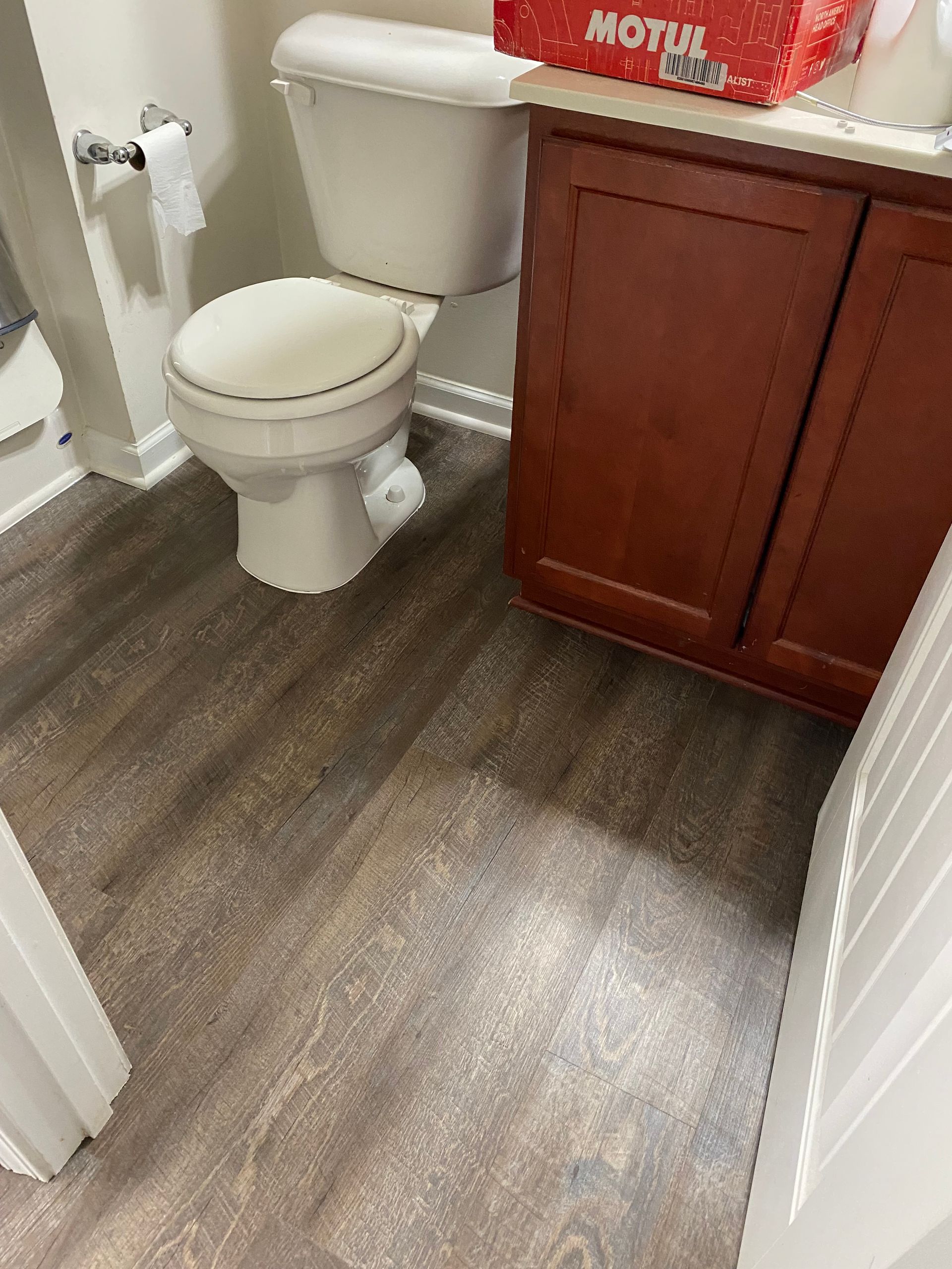 A bathroom with a toilet , sink and a box that says motul on it.