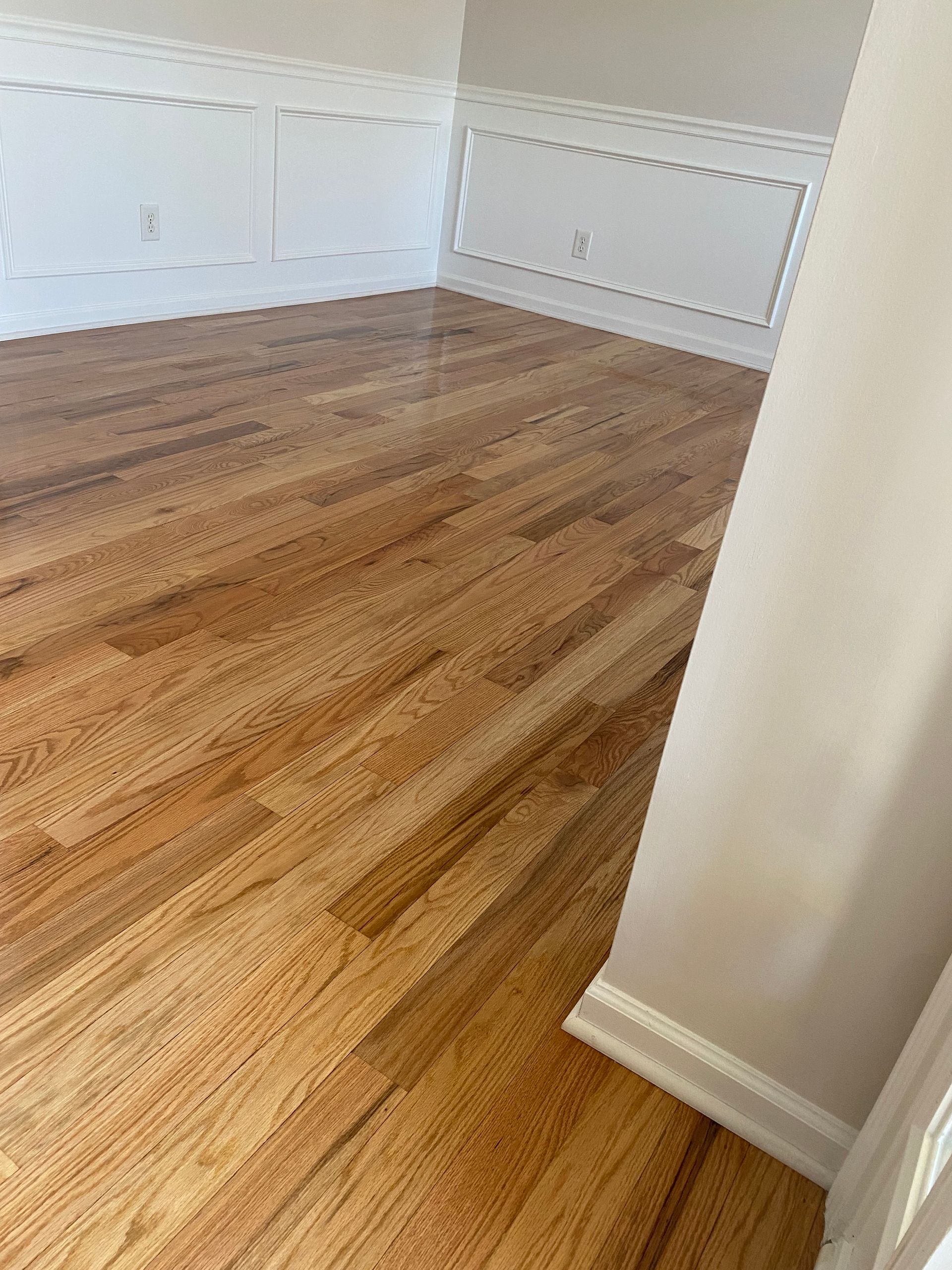 A room with hardwood floors and white trim in a house.