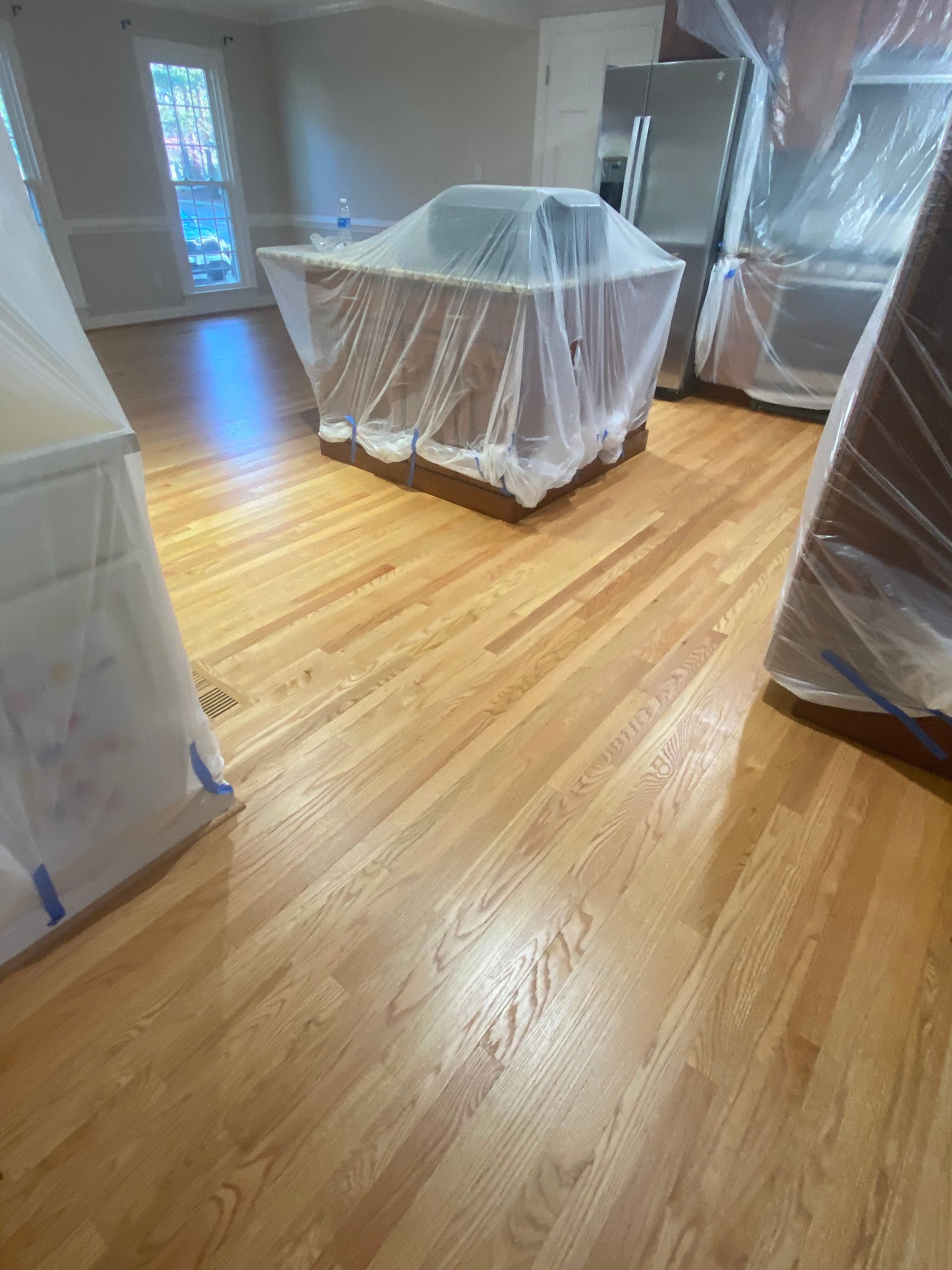 A wooden floor in a room with plastic covering it.