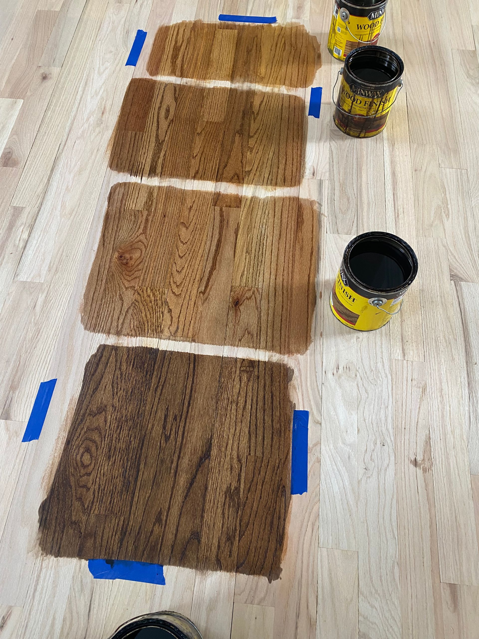 A wooden table with four pieces of wood and four cans of paint on it.