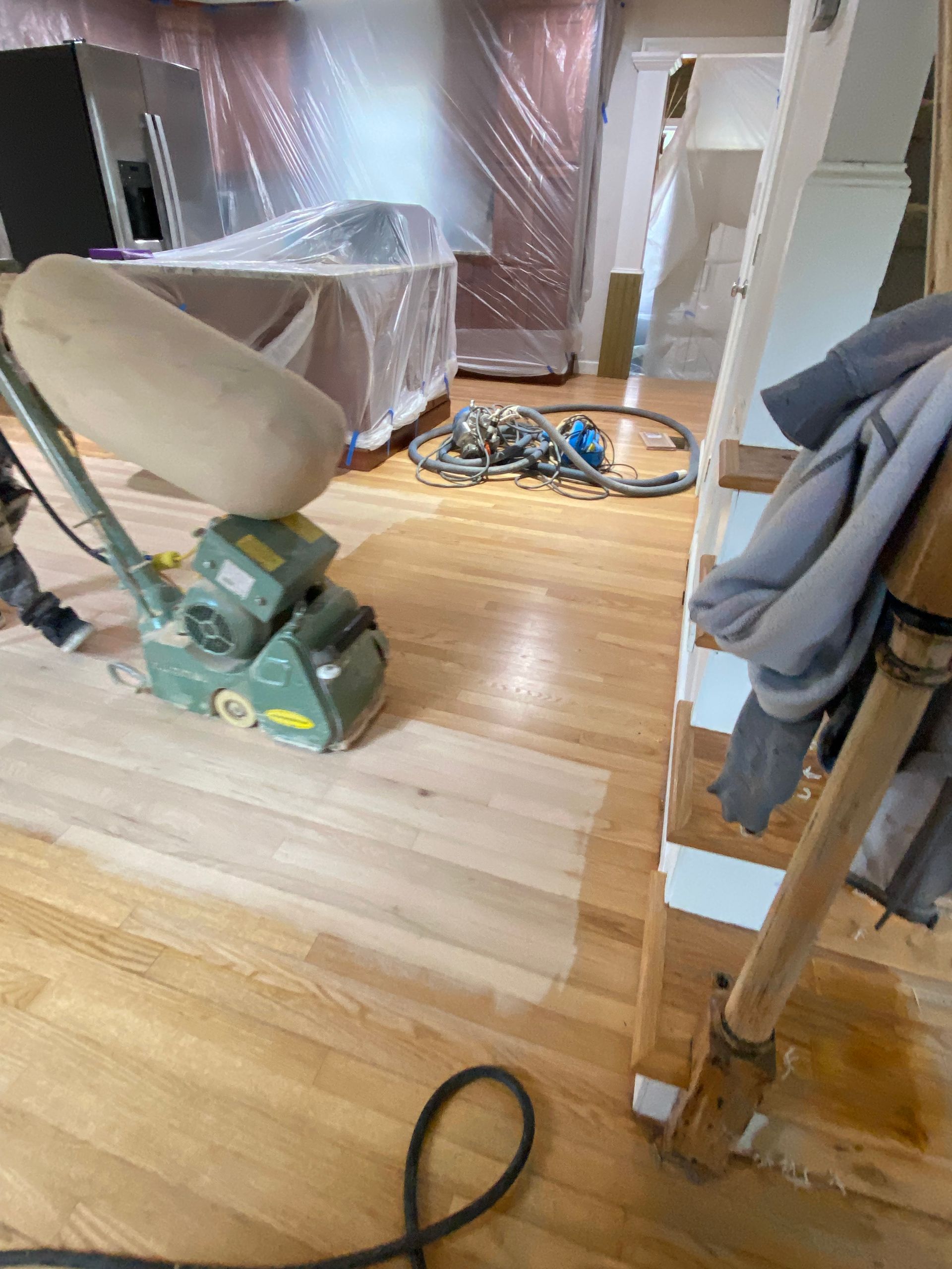 A person is sanding a wooden floor with a machine.