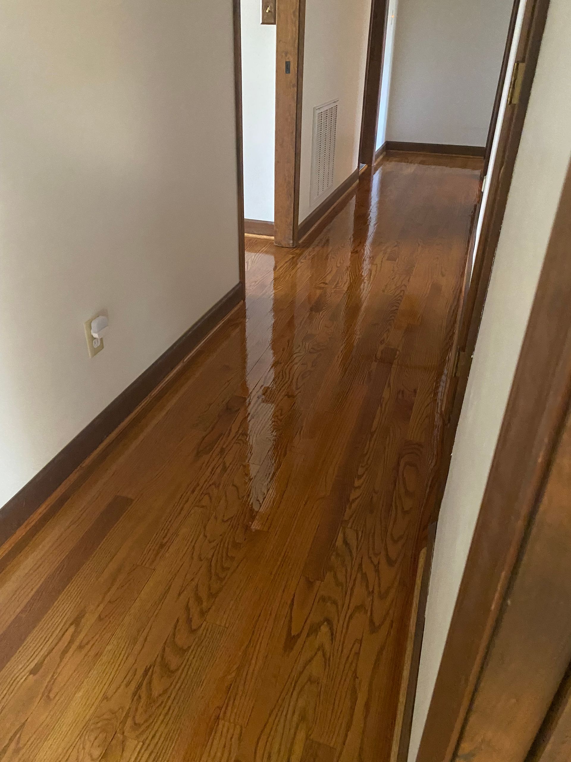 A hallway with hardwood floors and white walls.