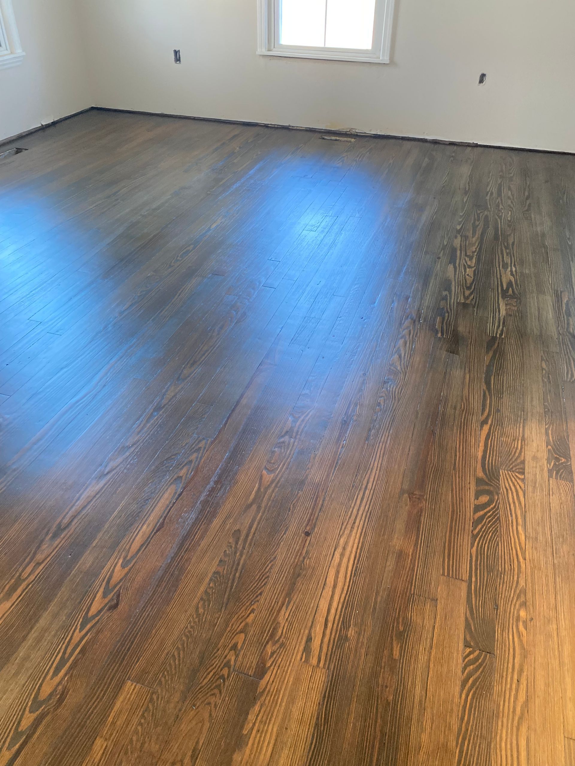 A large room with hardwood floors and a window.