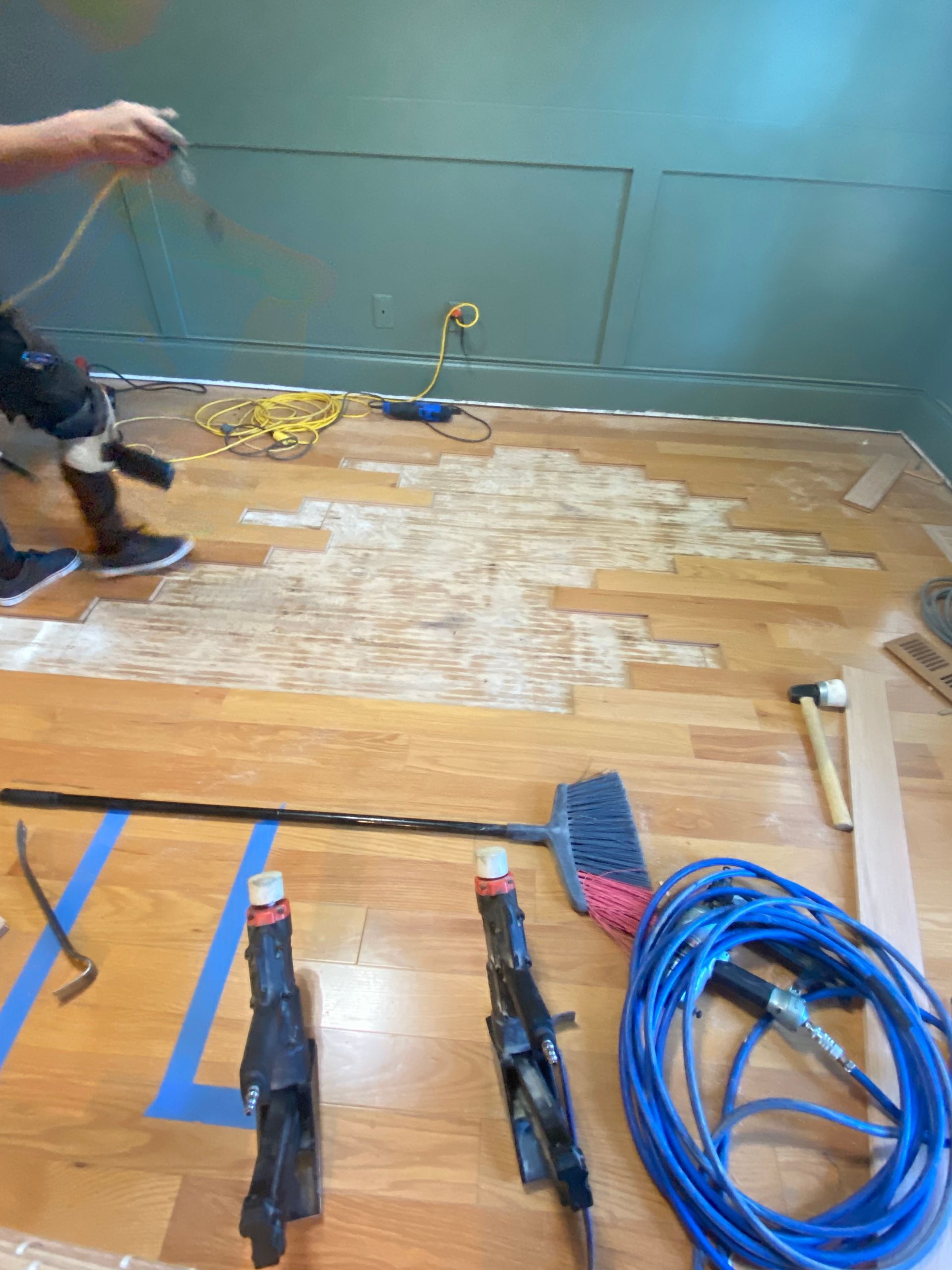 A person is working on a wooden floor with tools.