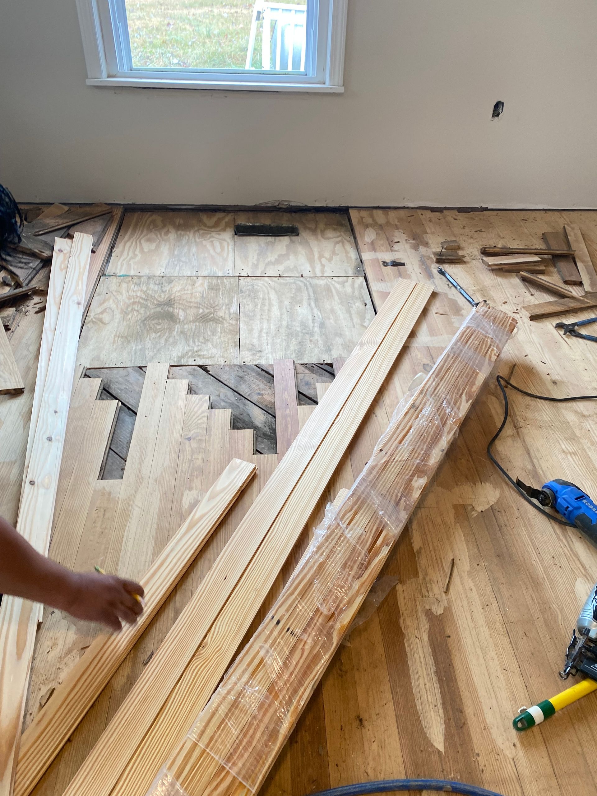 A person is working on a wooden floor in a room.
