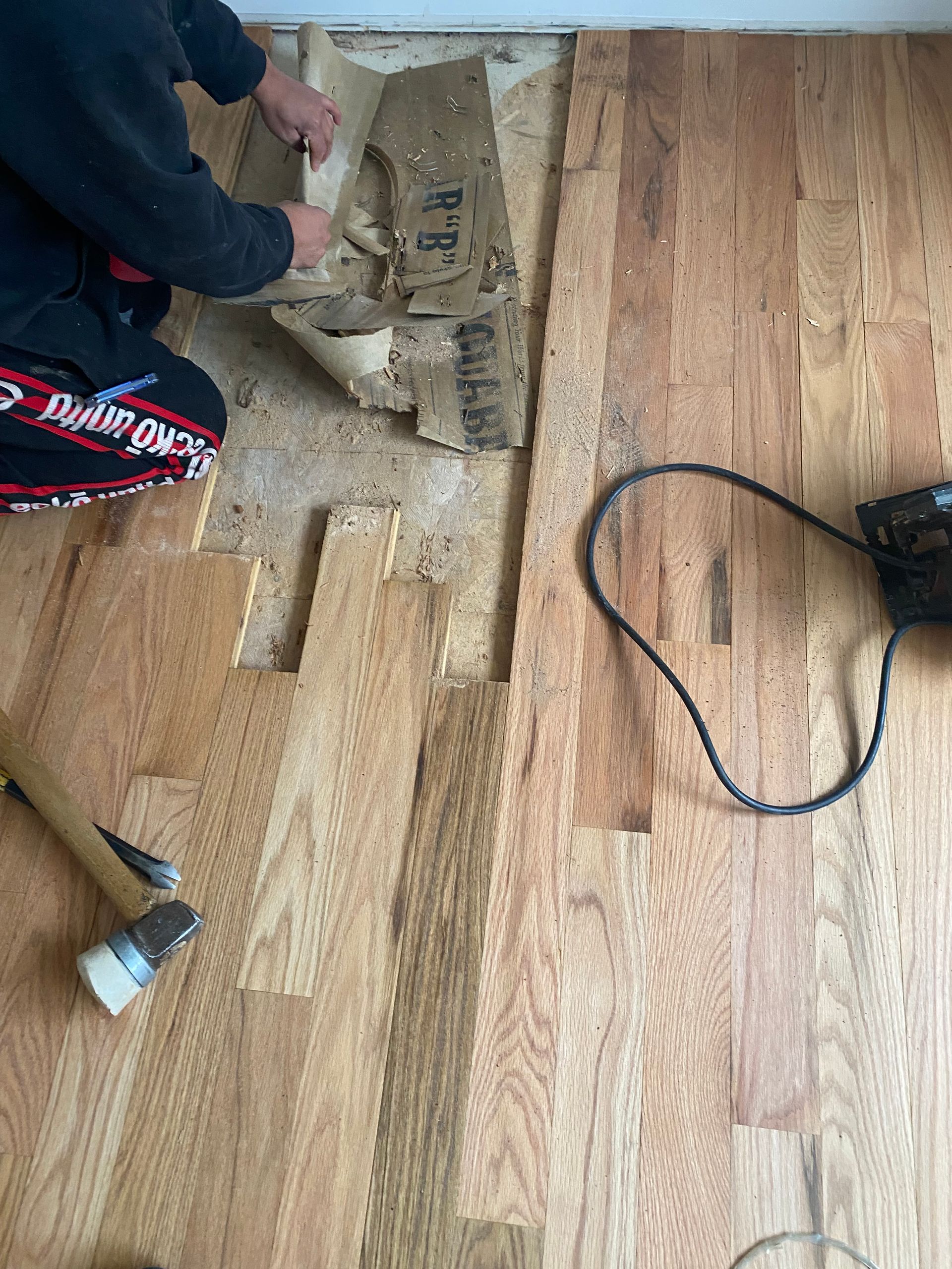 A person is kneeling down on a wooden floor.