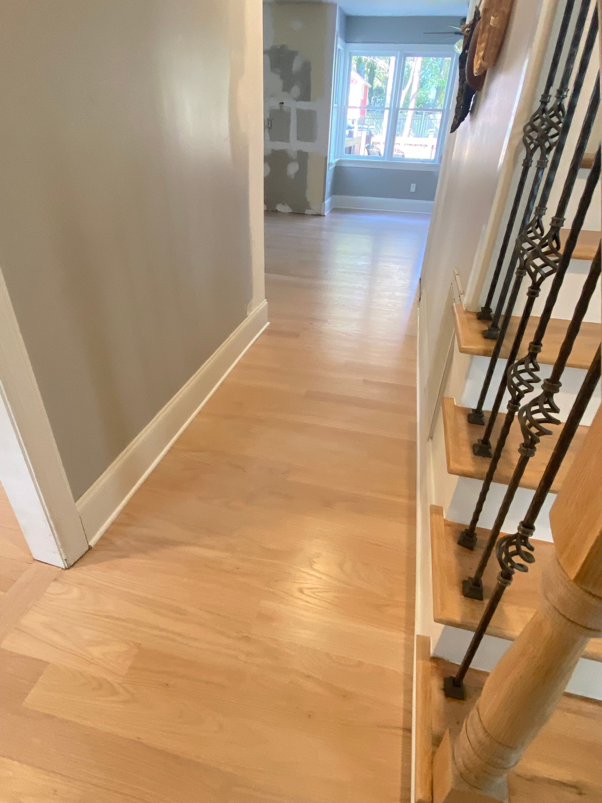 A hallway with wooden floors and stairs in a house.