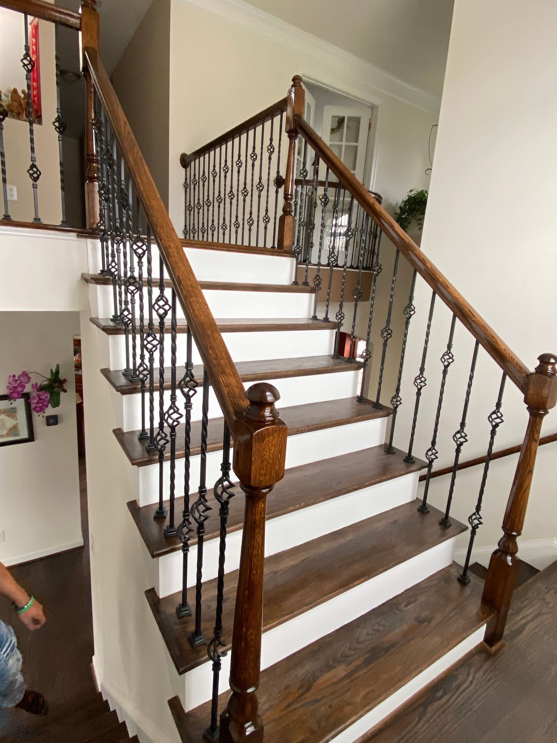 A wooden staircase with white steps and a wrought iron railing