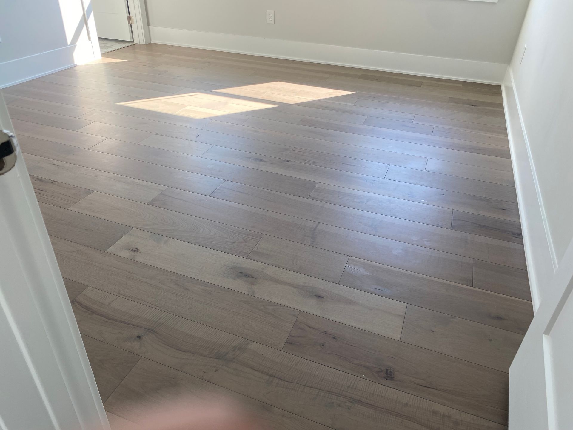 Empty room with light wood flooring and a sunlit patch on the floor