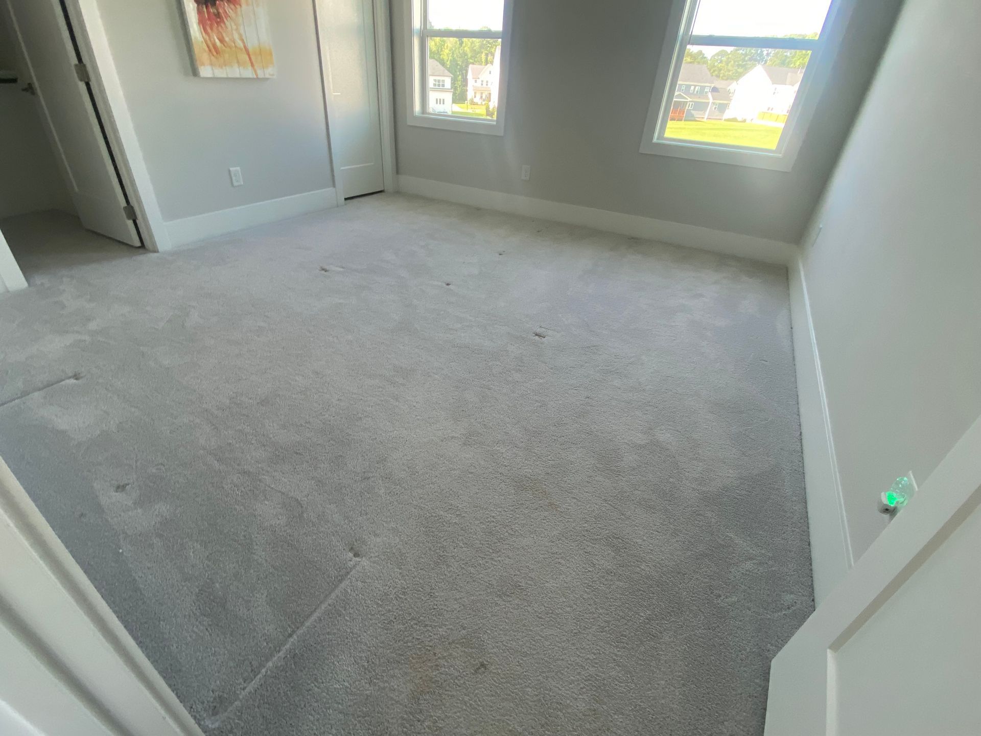 Empty carpeted room with white walls and two windows letting in daylight