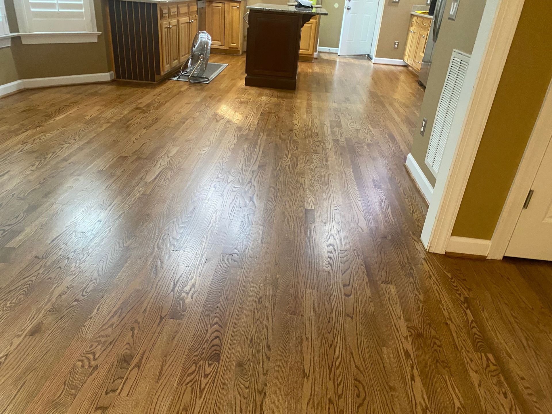 Empty room with hardwood floors, a wooden cabinet, and white trim near a doorway.