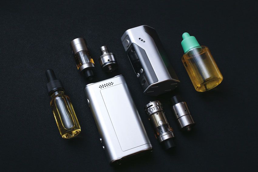 A group of electronic cigarettes and bottles of e liquid on a table.