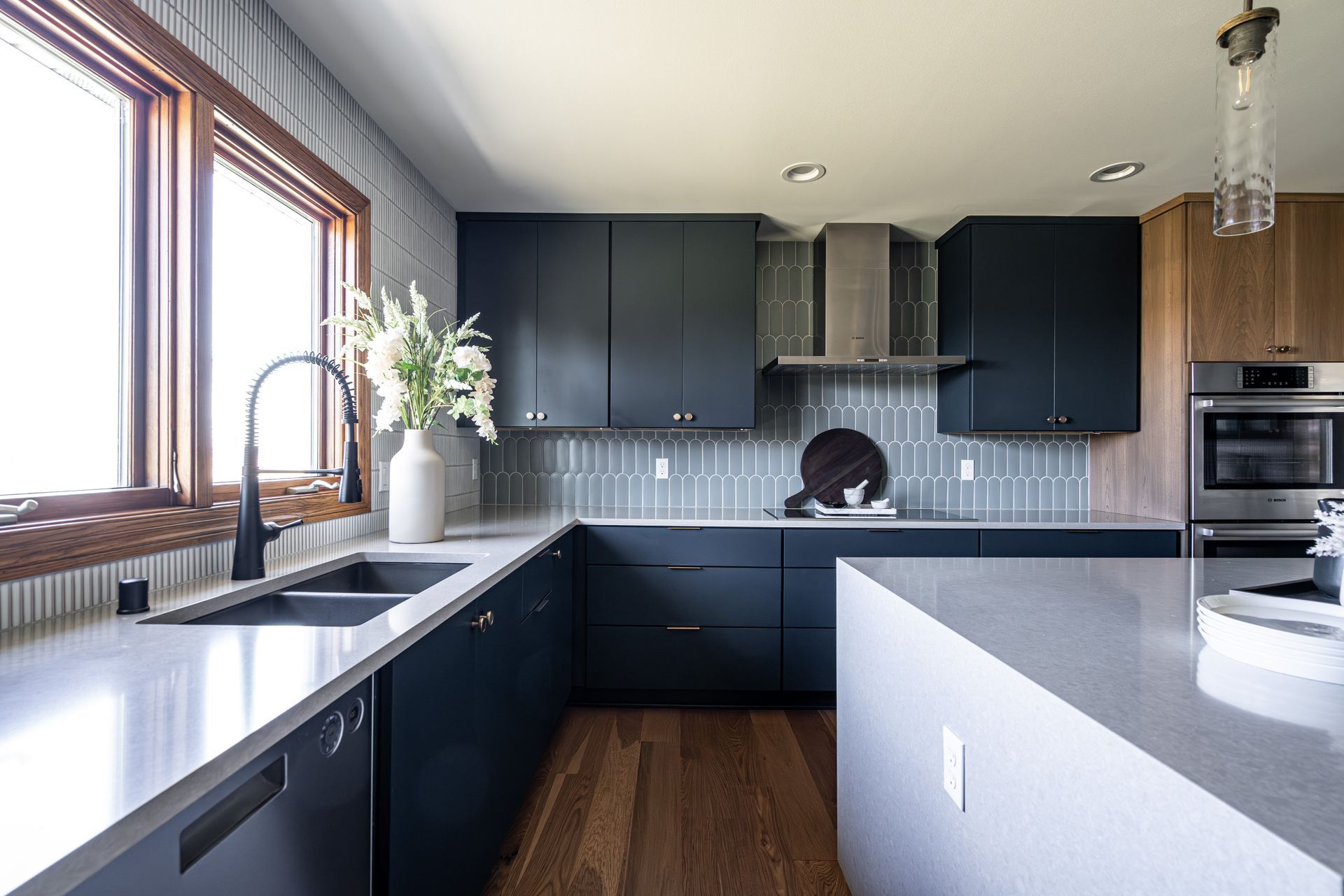 A kitchen with black cabinets, stainless steel appliances, a sink, and a large island.