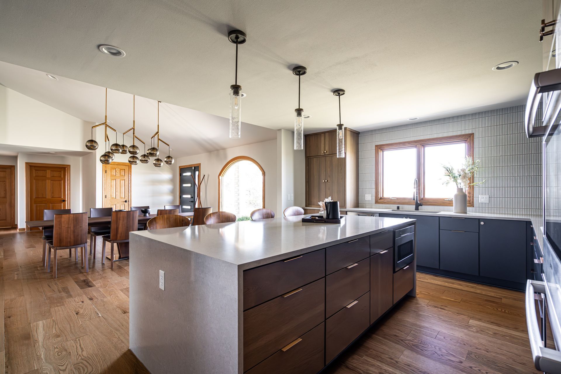 A kitchen with a large island in the middle and a dining room in the background.