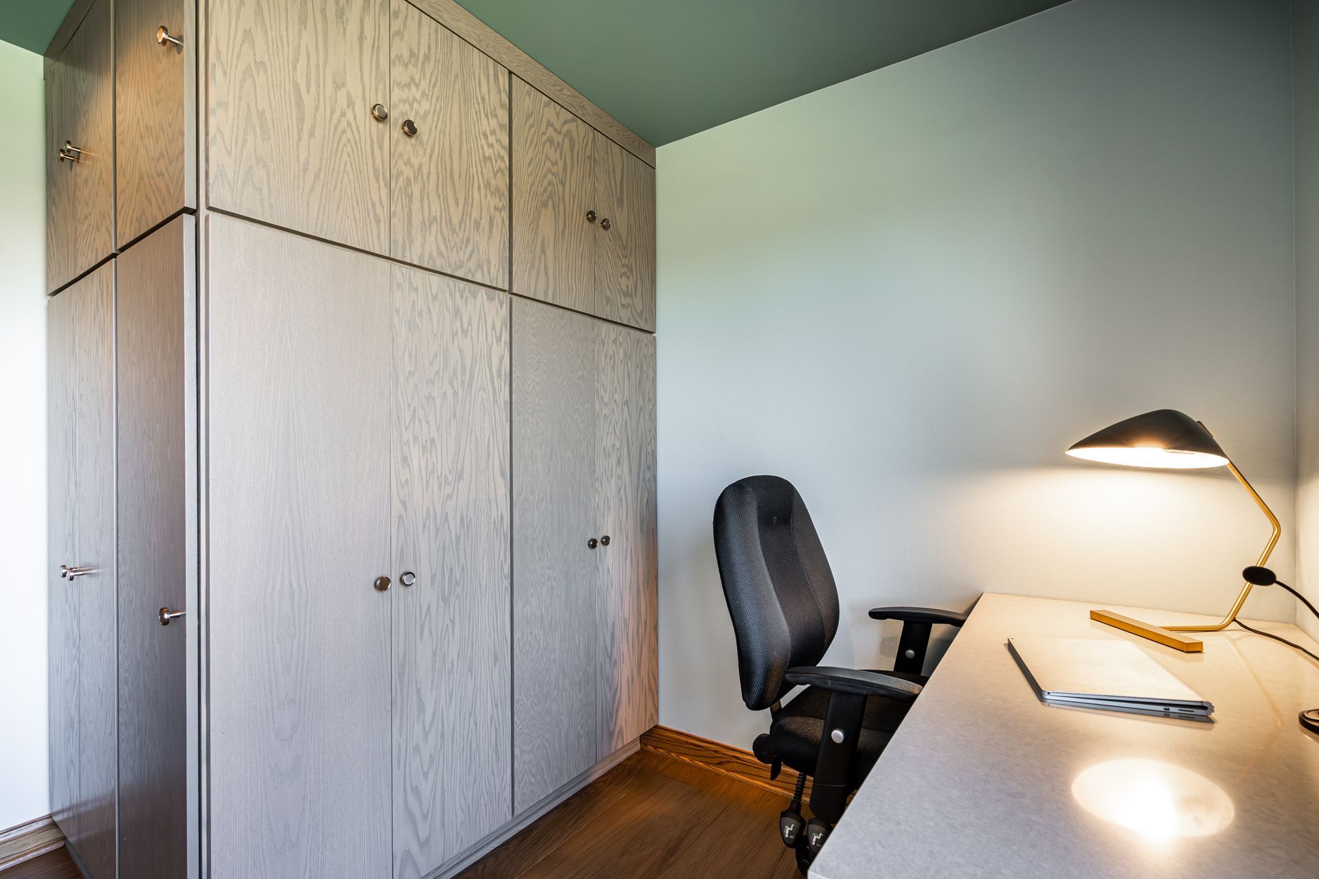 There is a desk with a chair and a lamp in the room.