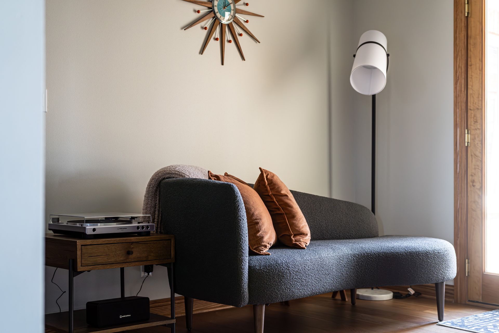 A living room with a couch and a clock on the wall.