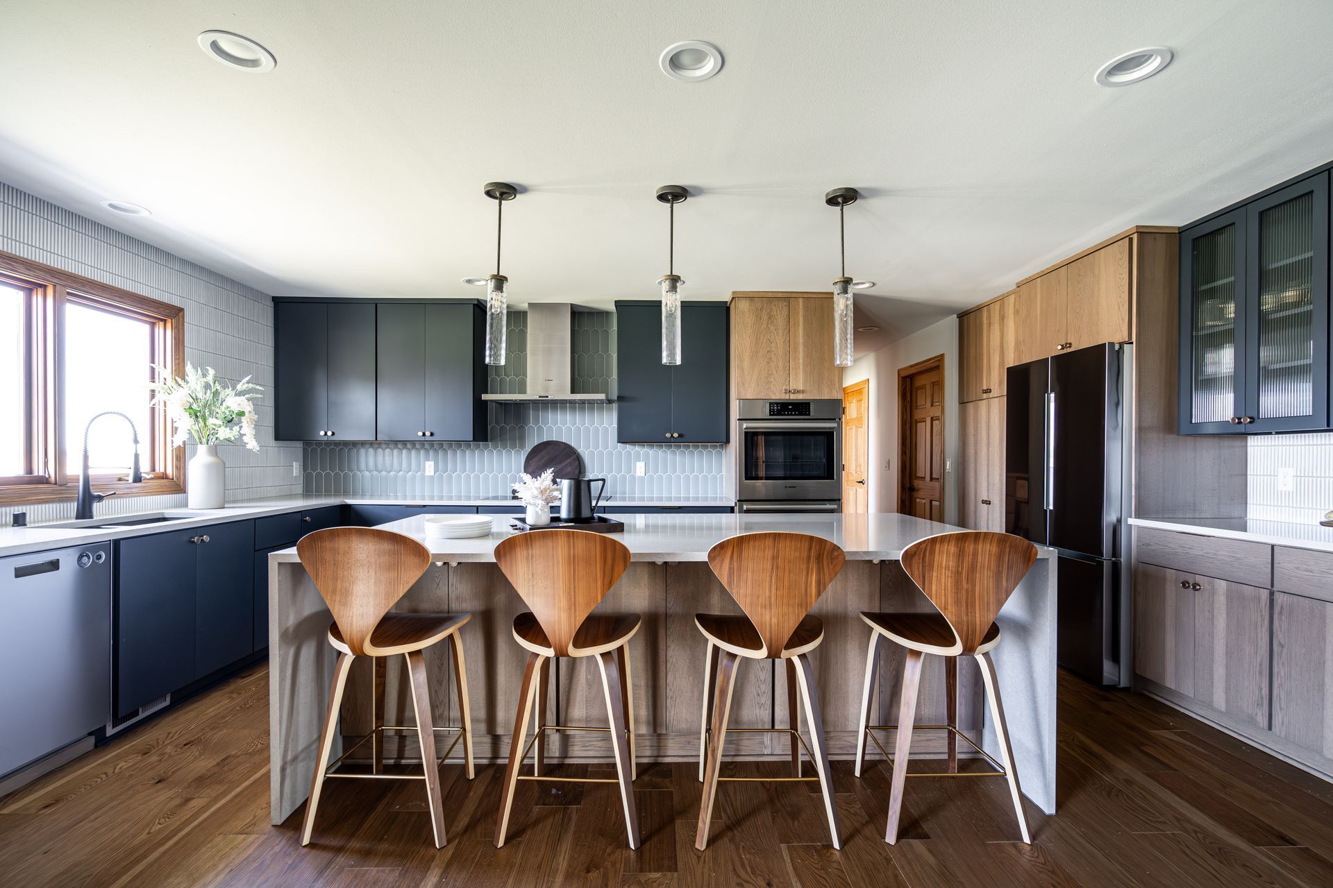 A kitchen with stools and a large island in the middle.