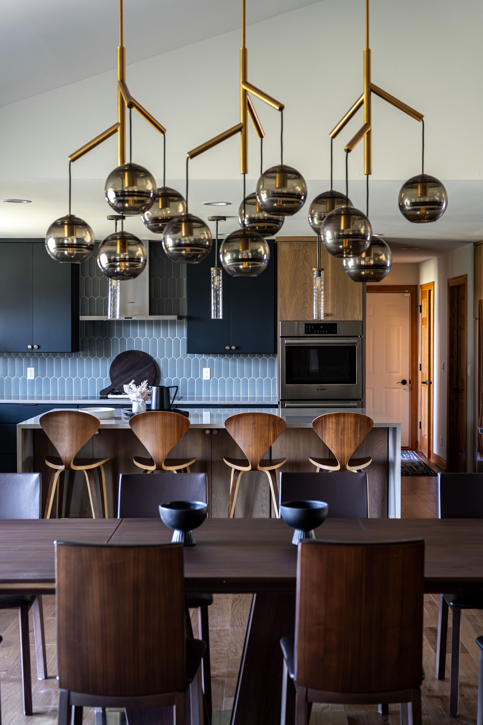 A dining room with a table and chairs and a kitchen in the background.