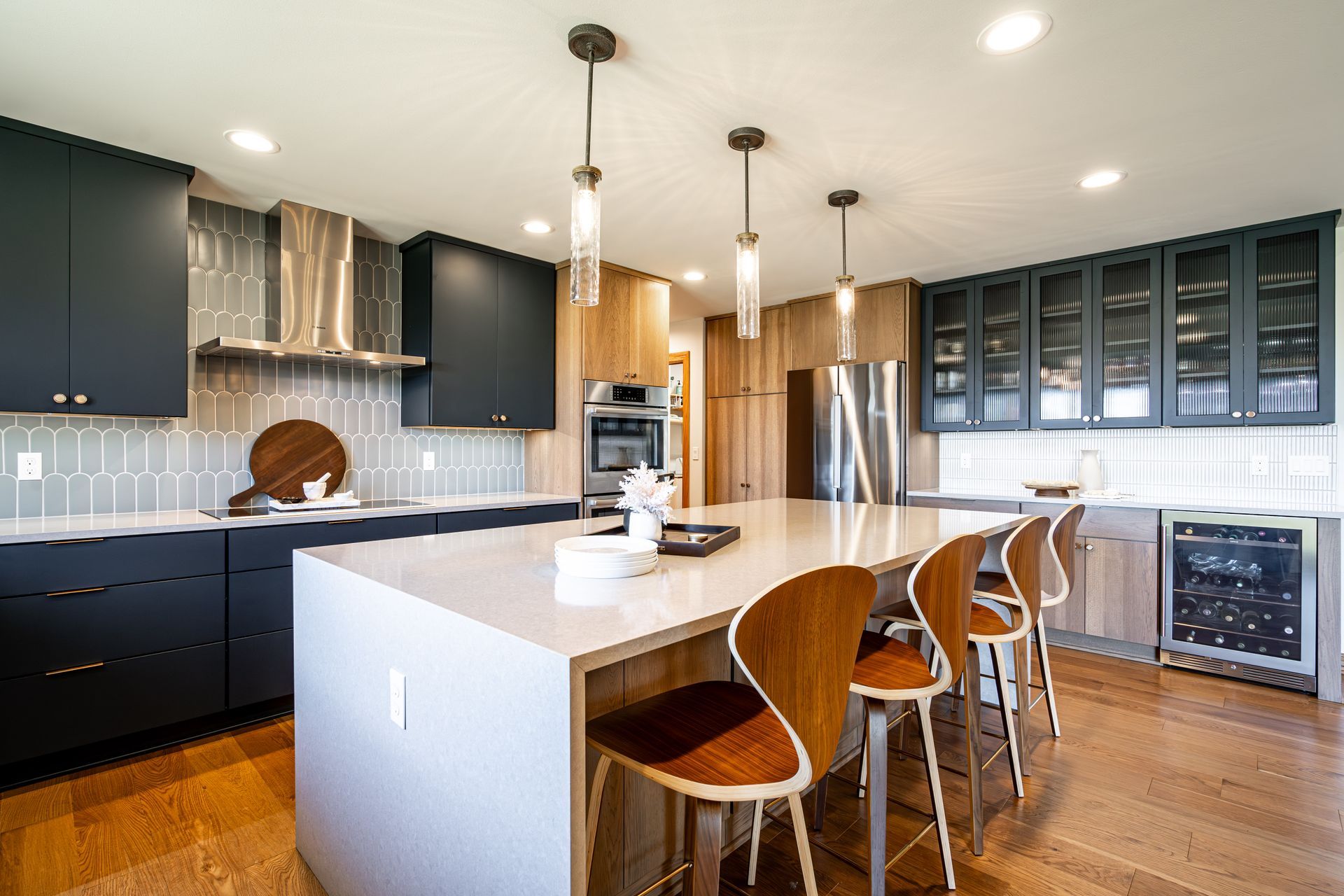 A kitchen with a large island and chairs in it.