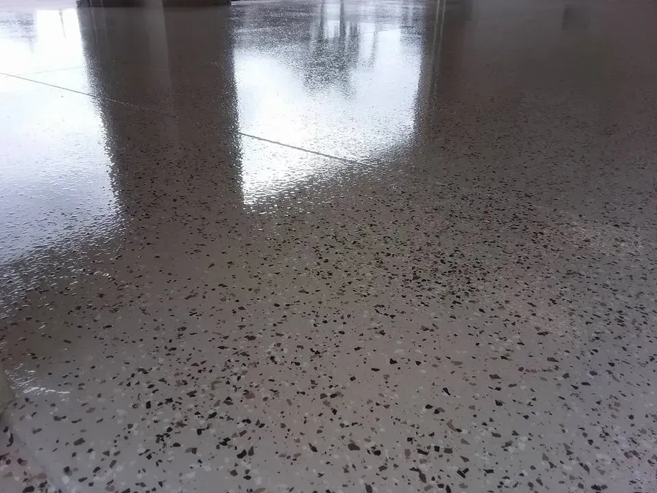Polished concrete floor with speckled aggregate, reflecting overhead structures.