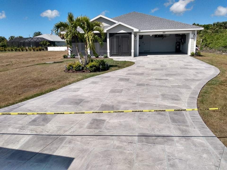 Driveway leading to a house with a gray roof and garage. Yellow caution tape across the driveway.