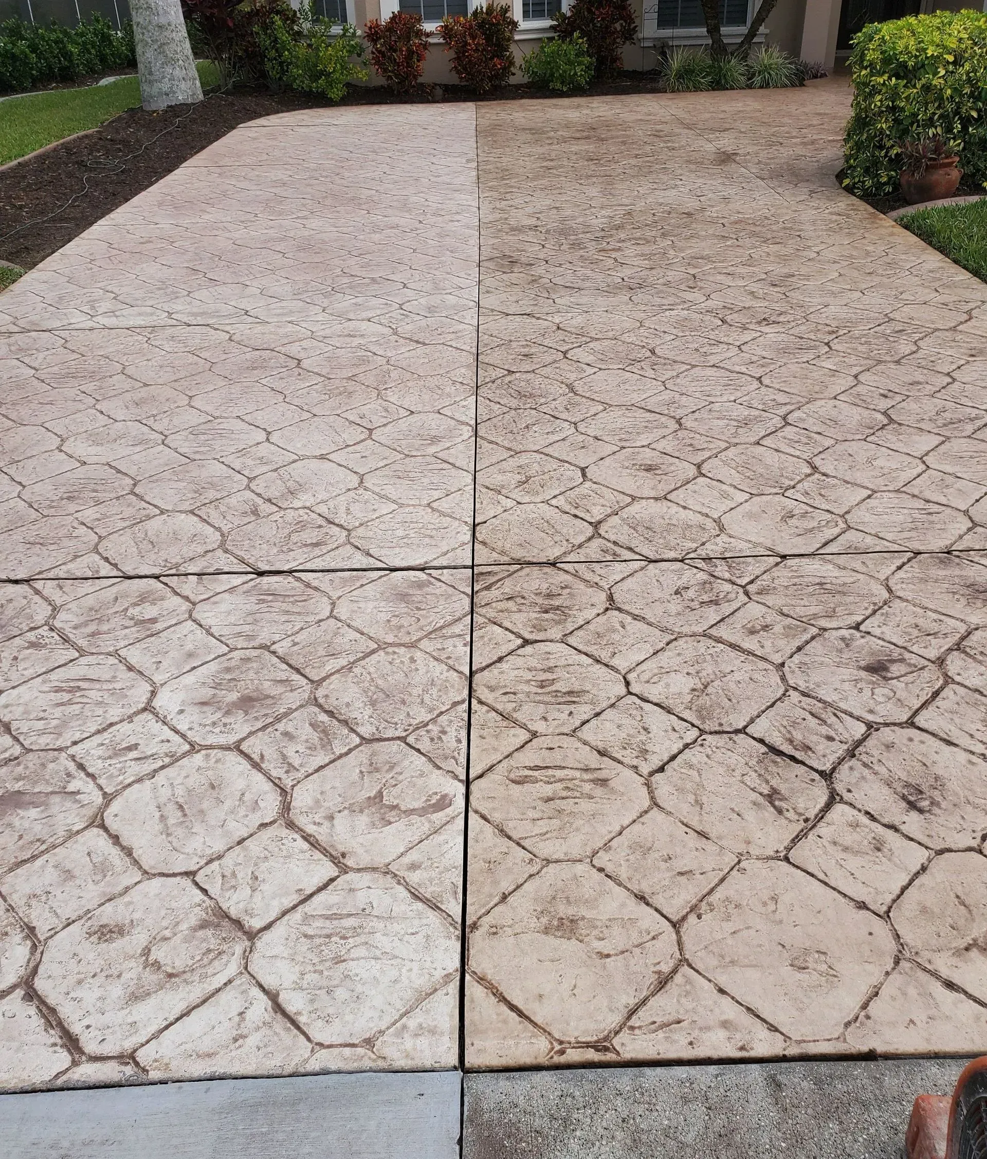 Driveway, half cleaned, showing stamped concrete before/after power washing.