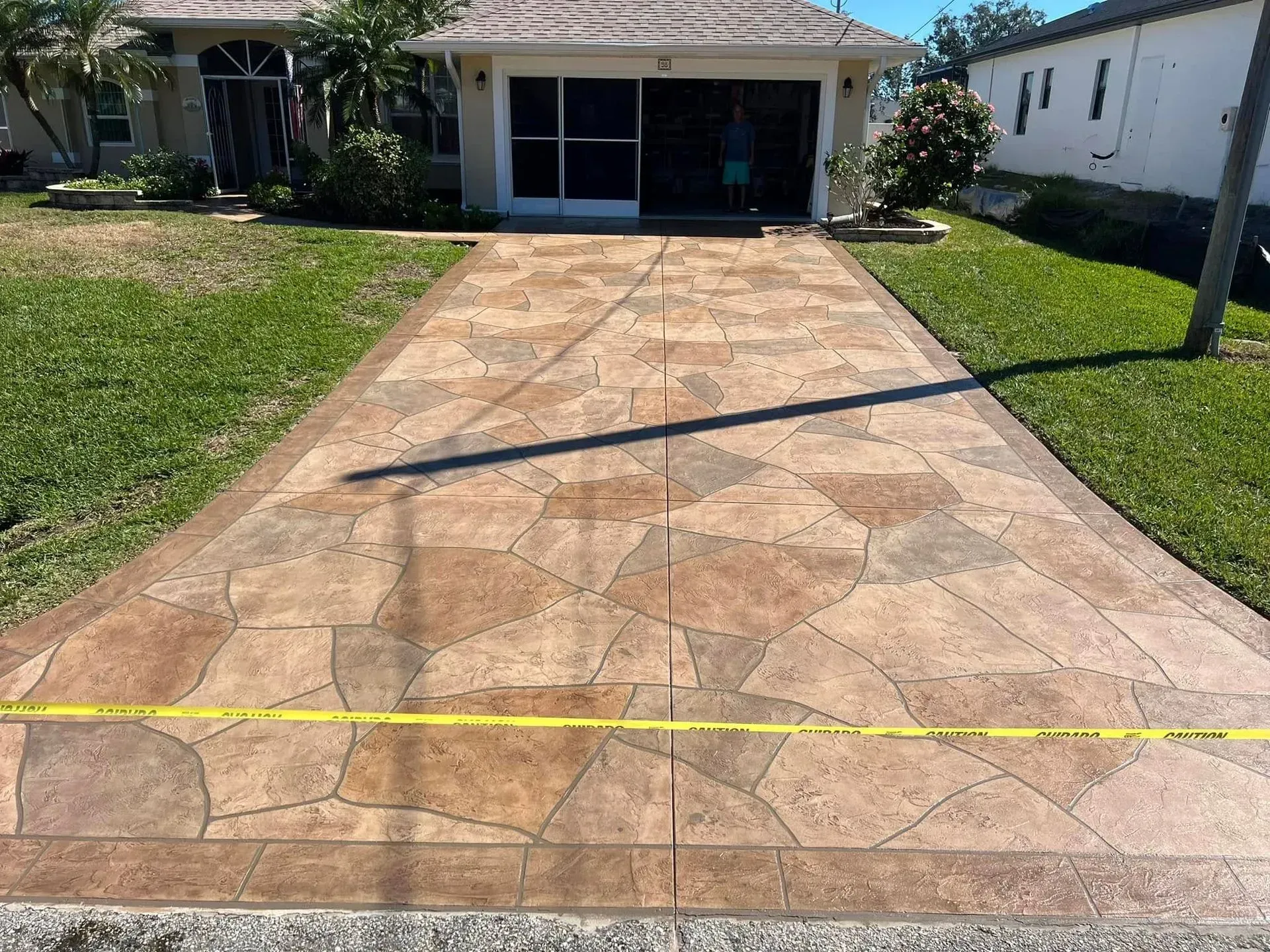 Stamped concrete driveway with flagstone pattern, brown and tan hues, in front of a house.