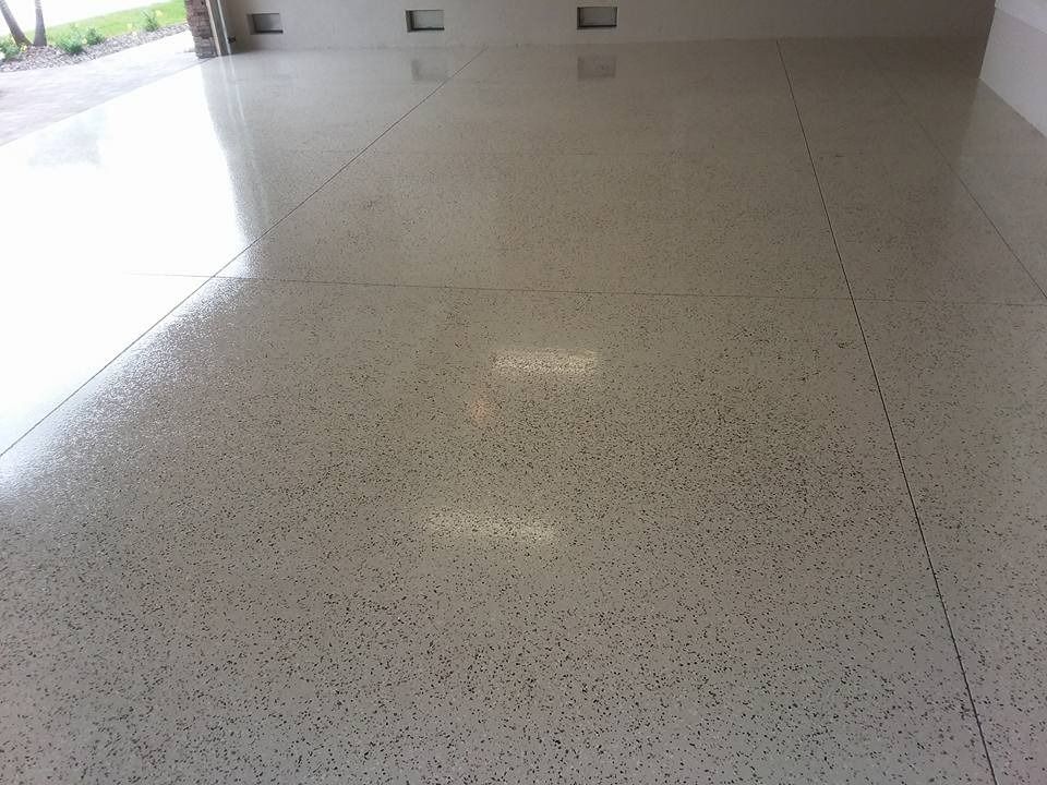 Polished concrete floor with small dark flecks, reflecting overhead light.