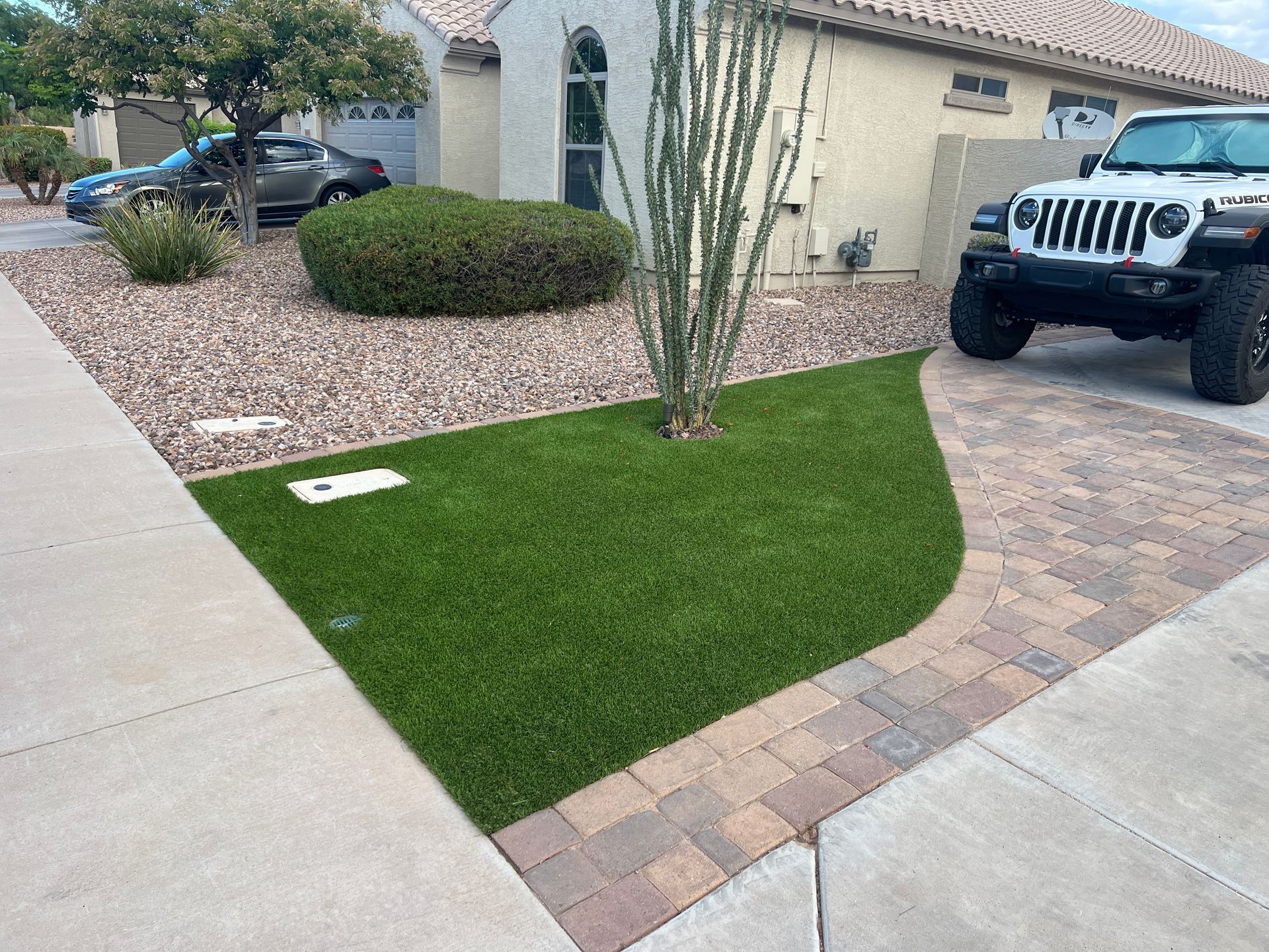 Front yard with green lawn, gravel, and a Jeep parked in the driveway.