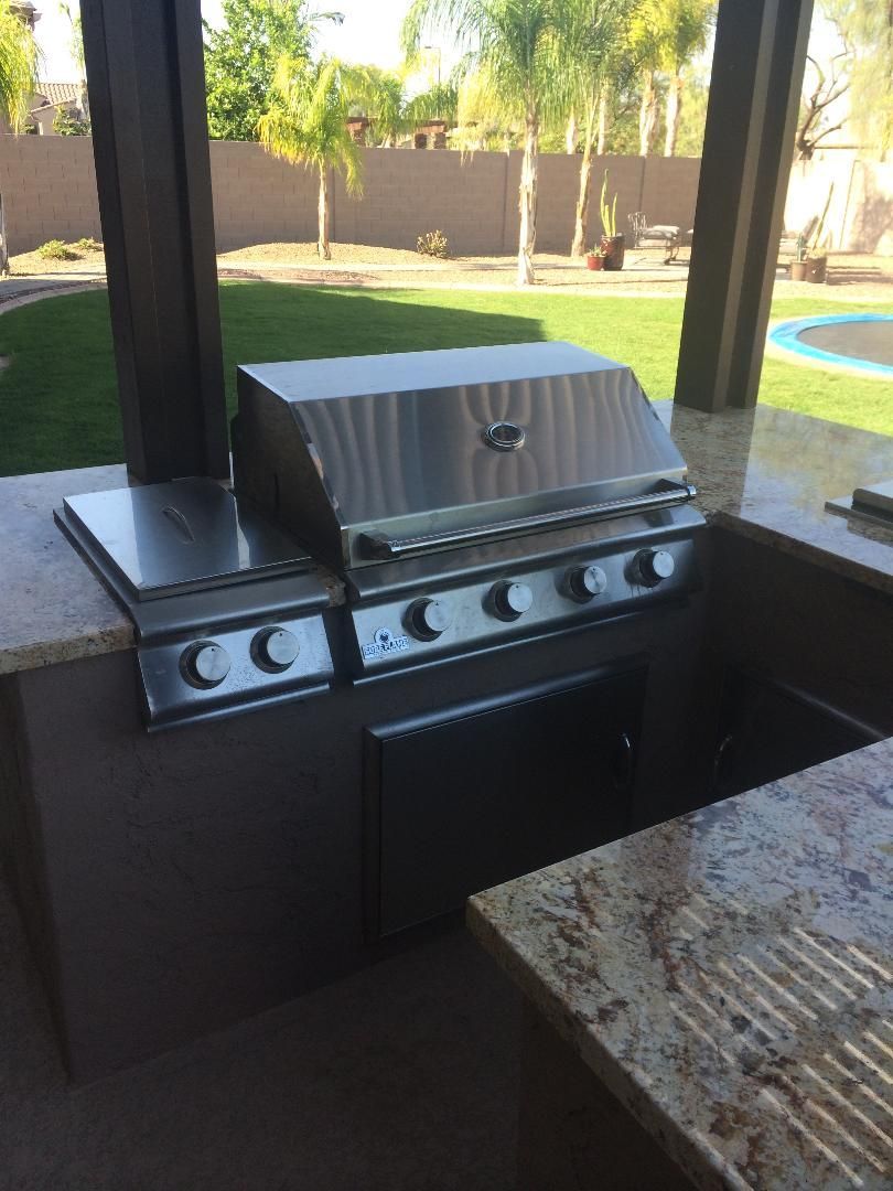 Outdoor kitchen with stainless steel grill, side burner, and granite countertop.