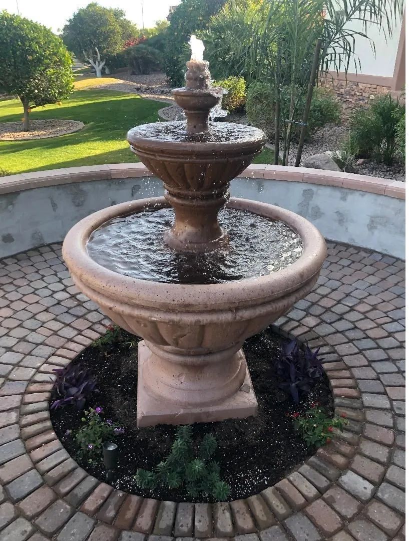 Stone tiered fountain in a brick patio, water flowing.