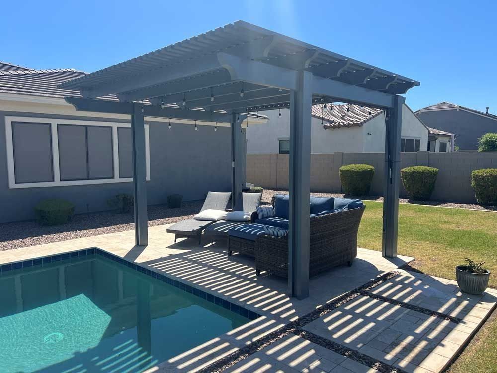 Pergola over outdoor seating by a pool in a backyard on a sunny day.