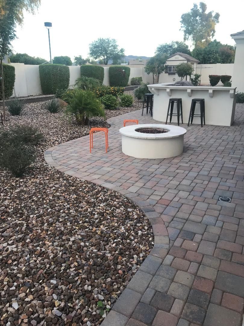 A backyard patio with a fire pit, bar, and landscaping.