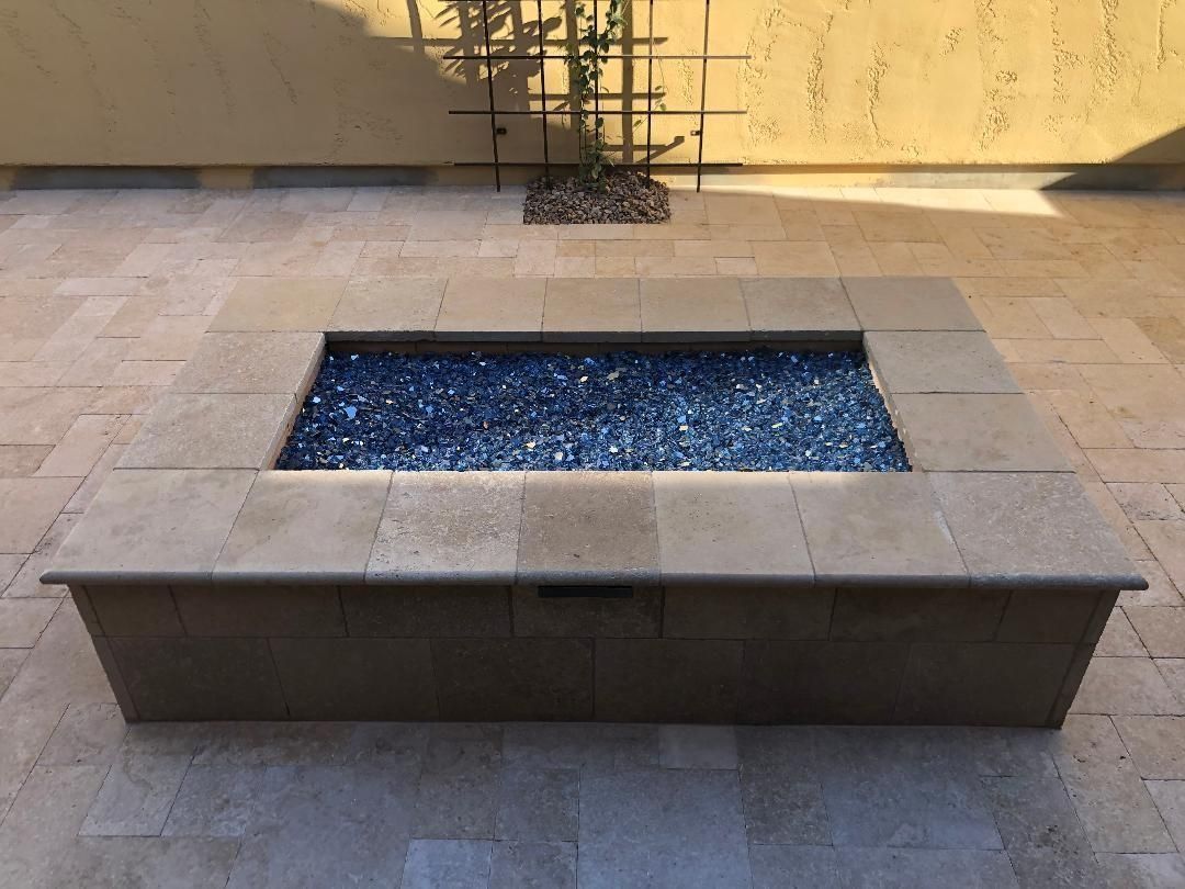 Stone fire pit with blue glass, set on stone tiles.