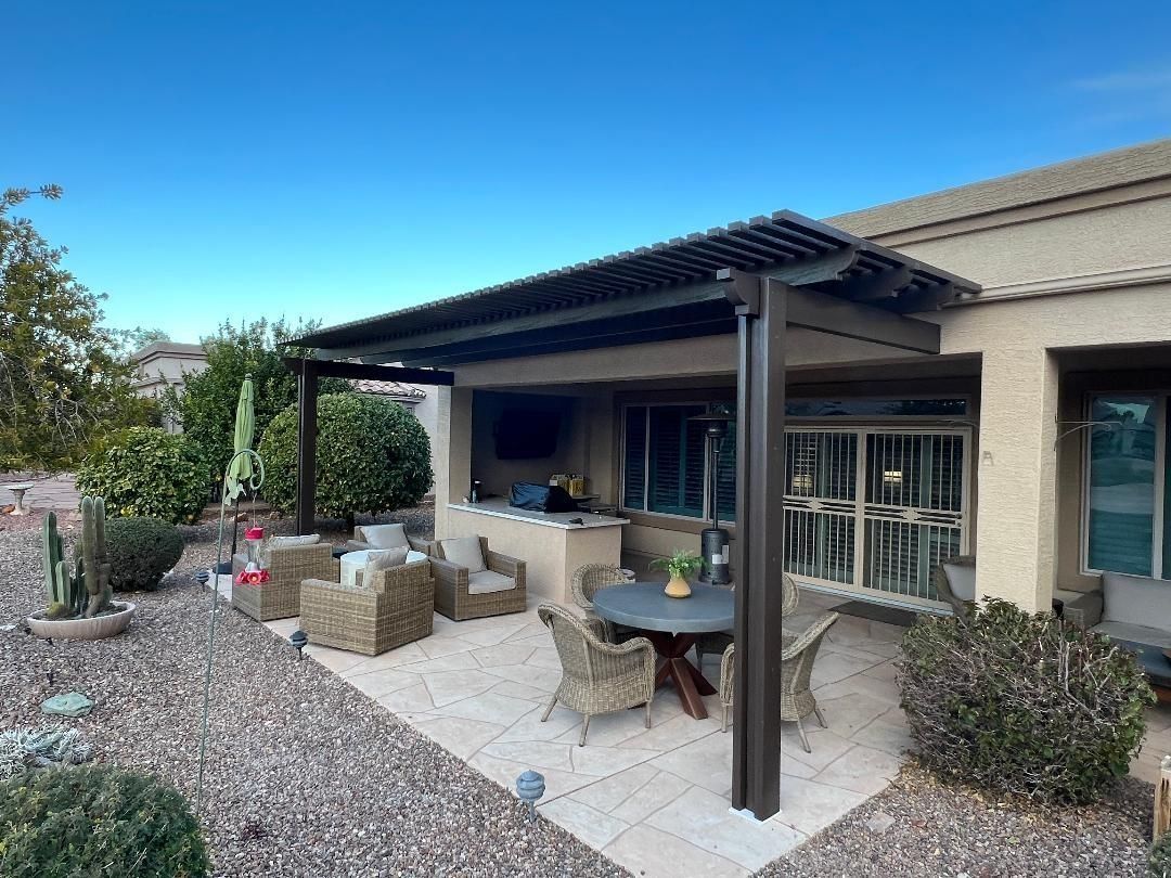 Patio with dark pergola, seating, outdoor kitchen, and landscaping.