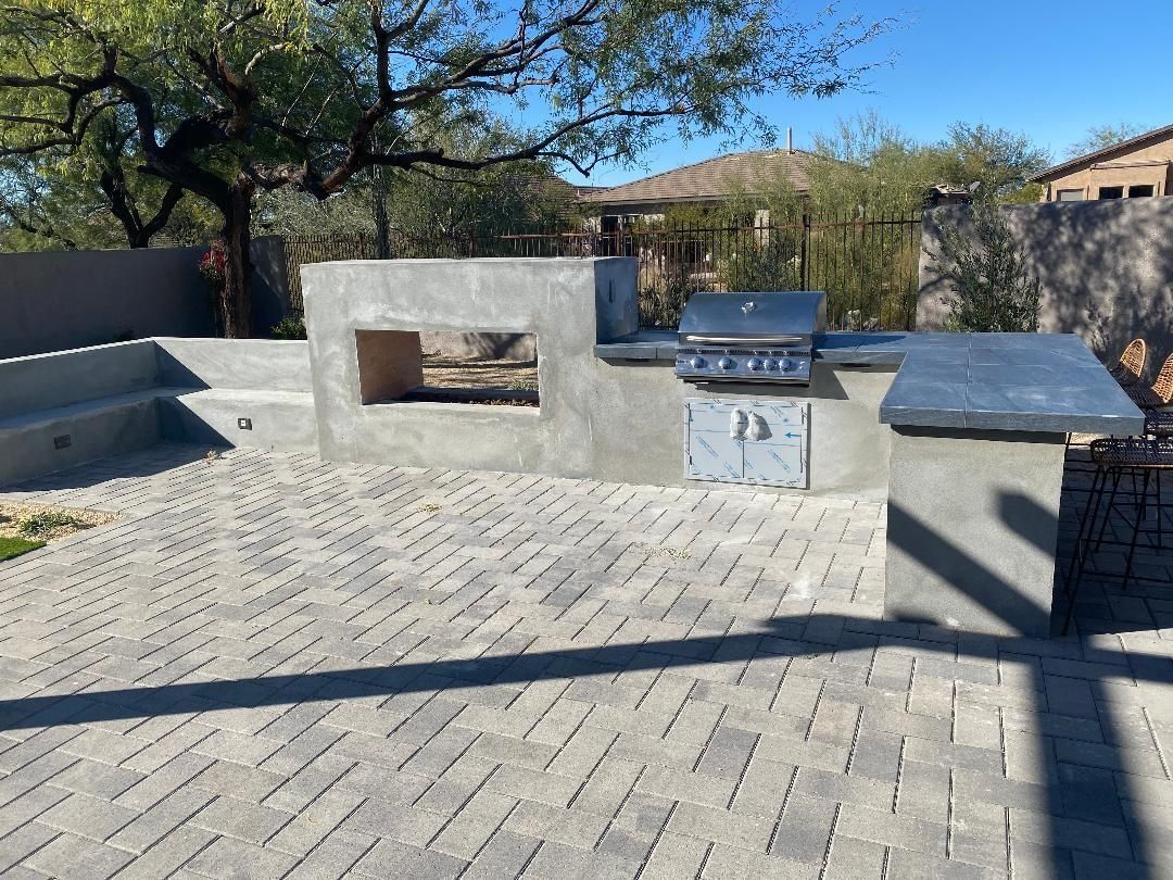 Outdoor kitchen with grill, fireplace, and gray brick patio.