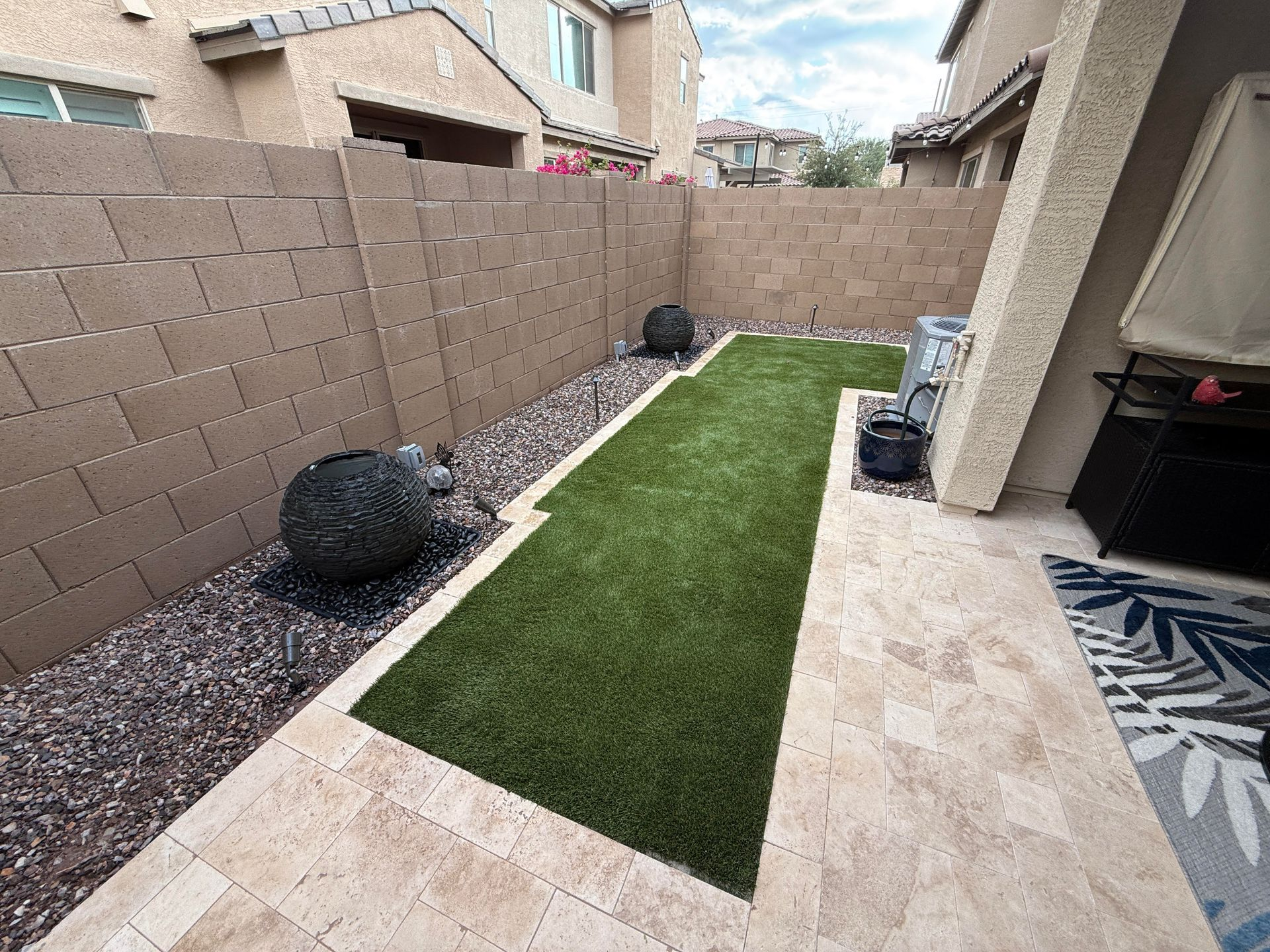 Small backyard with artificial turf, stone path, and decorative rocks.