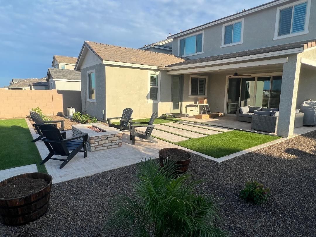 Backyard with a stone fire pit, seating, patio, and two-story house.