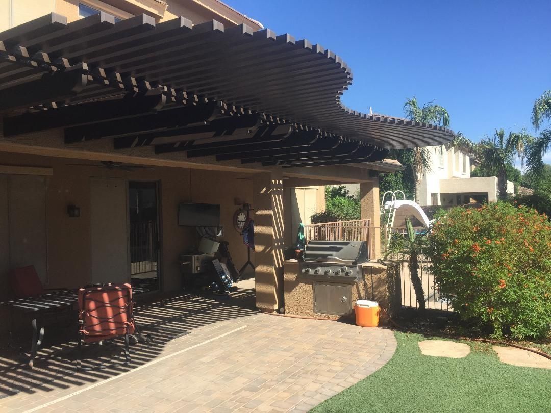 Patio with pergola, BBQ, and outdoor furniture on a sunny day.