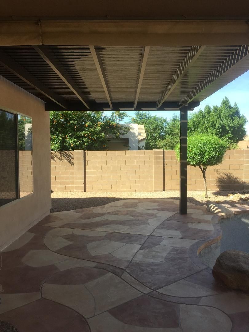 Patio with shaded roof, textured concrete floor, and a block wall in the background.