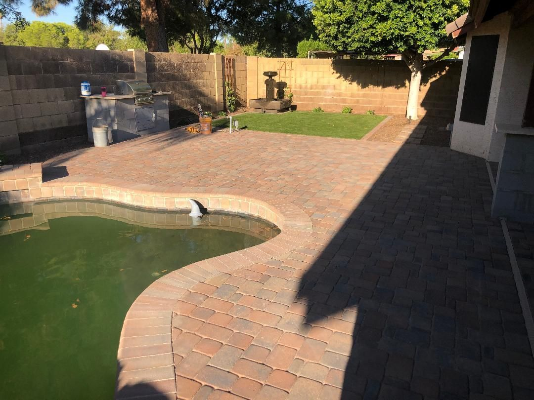 Brick patio surrounds a pool with green water. A small lawn and brick pathways lead to a fountain.