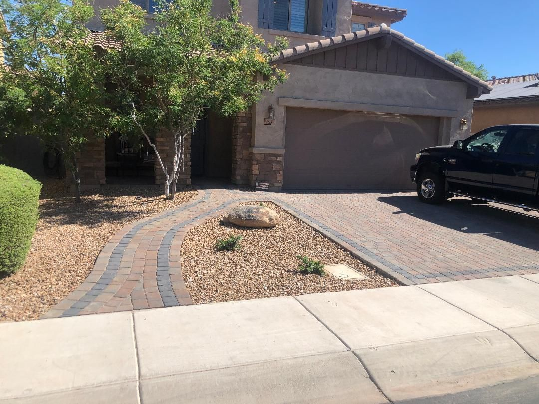 House exterior with driveway and brick walkway. Brown and tan colors. Black vehicle parked on the right.