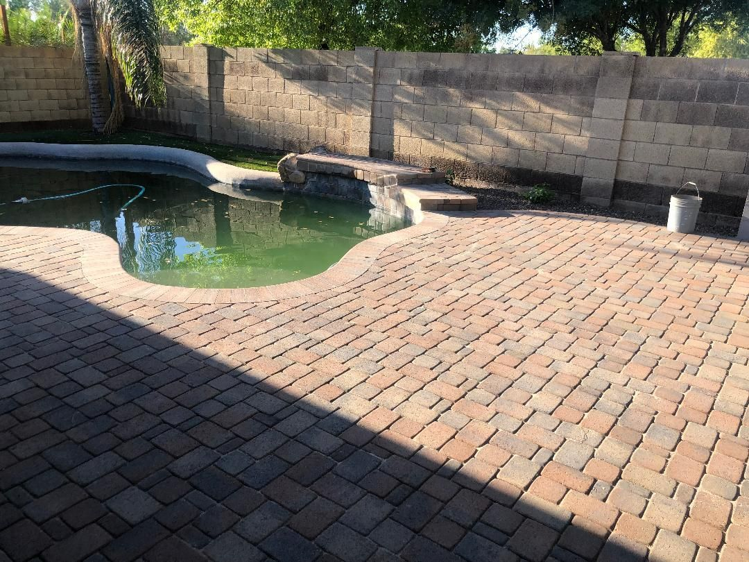 Brick patio with pool, stone wall, and bucket. The pool water is murky green.