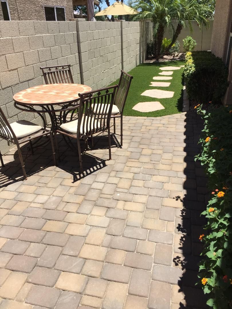 Patio with table, chairs, brick pavers, artificial turf, and a stone pathway.