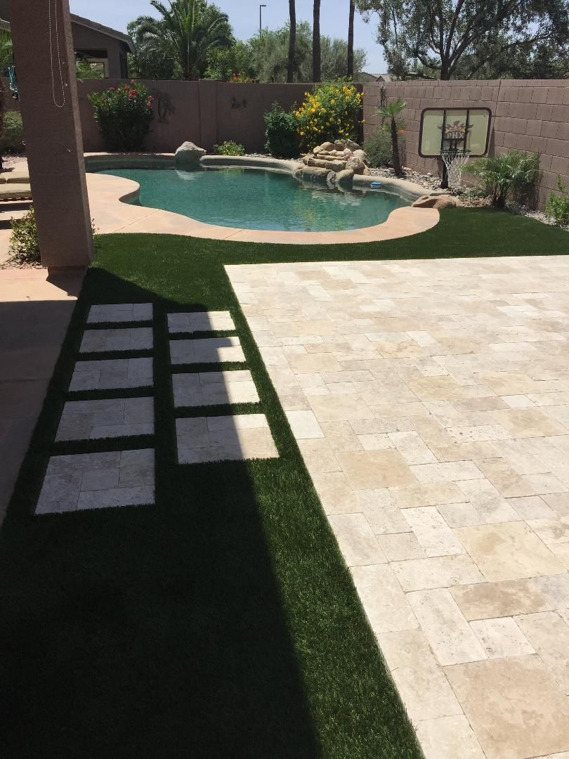 Backyard with a pool, patio, artificial turf, and stepping stones.