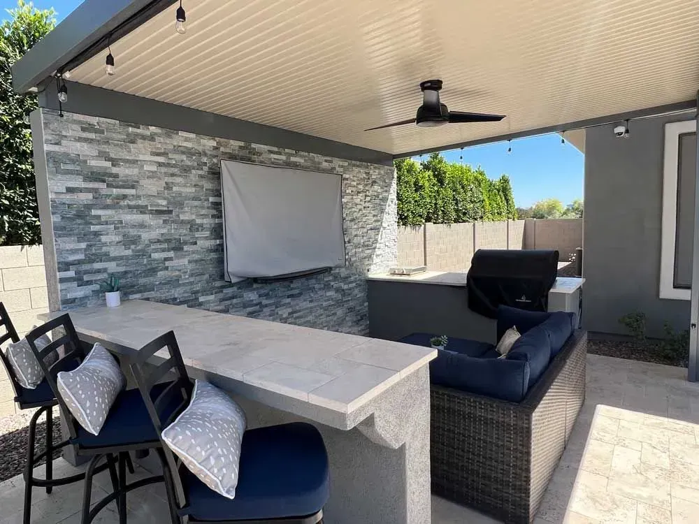 Outdoor patio with bar, grill, seating, stone accent wall, and ceiling fan.