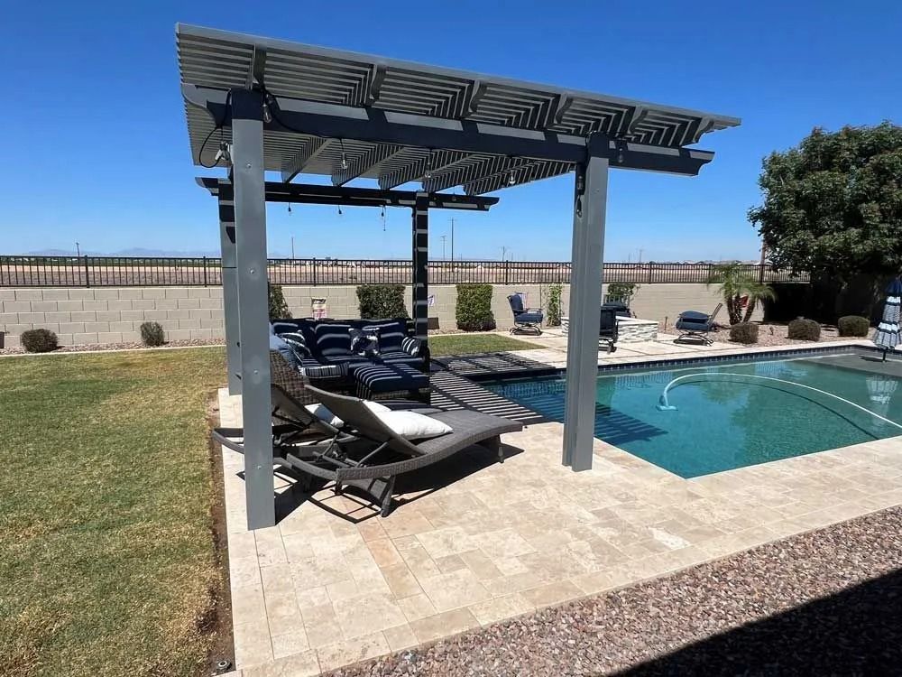 Poolside pergola with lounge chairs, blue water, and clear sky.