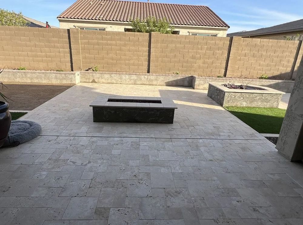 Patio with two fire pits, travertine flooring, and a brick wall.