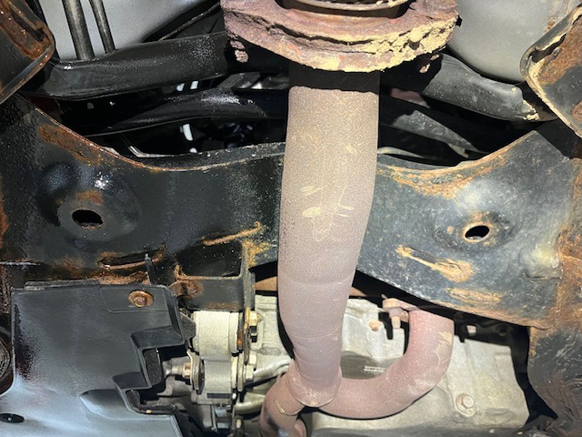 A close-up of a rusty exhaust pipe on a car
